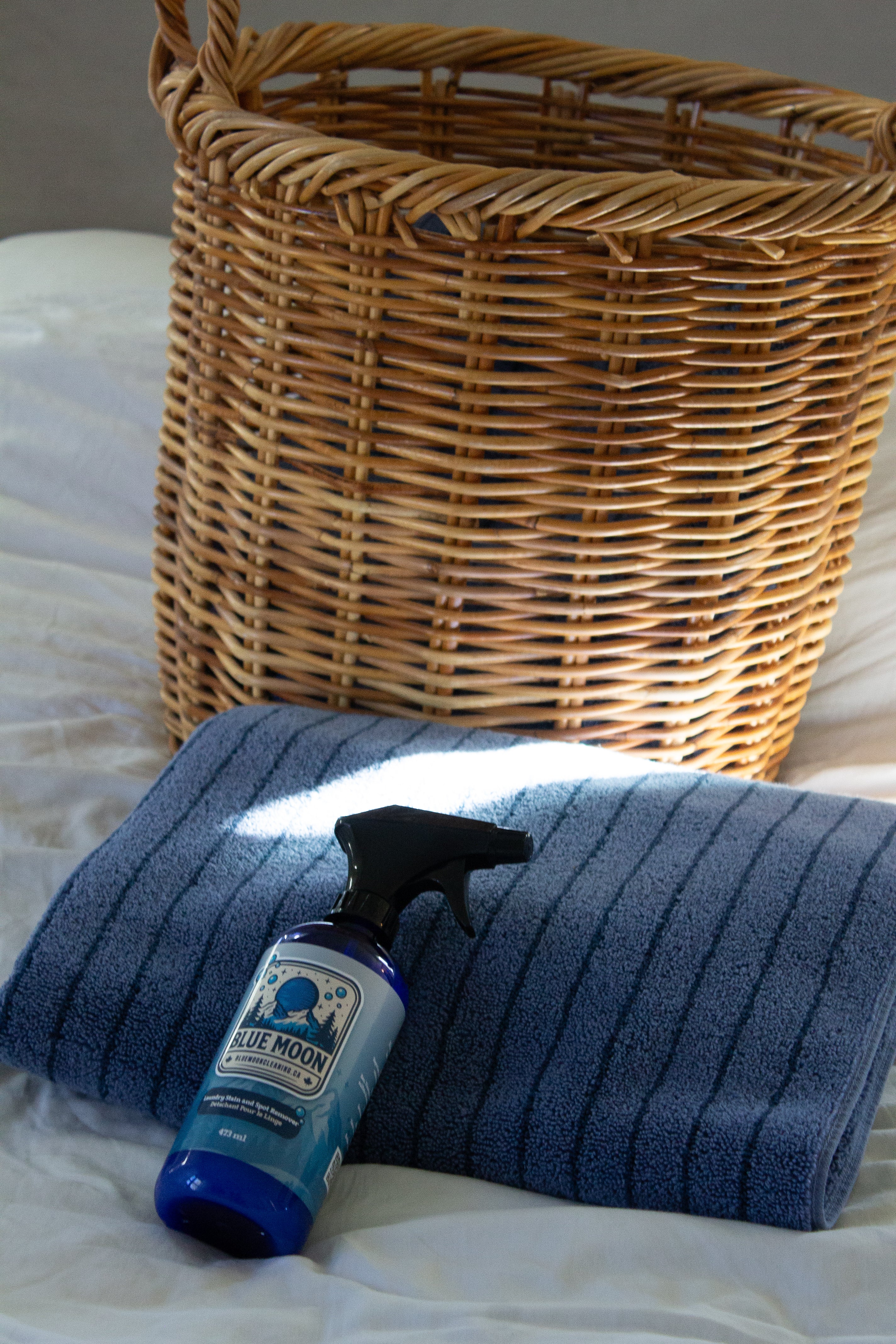 Wicker basket, blue towel, and Blue Moon bottle on a bed
